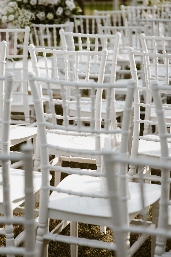 our-mission Rows of white chairs arranged outdoors for a wedding ceremony under natural sunlight.